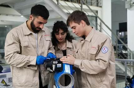 A group of people looking at a machineDescription automatically generated